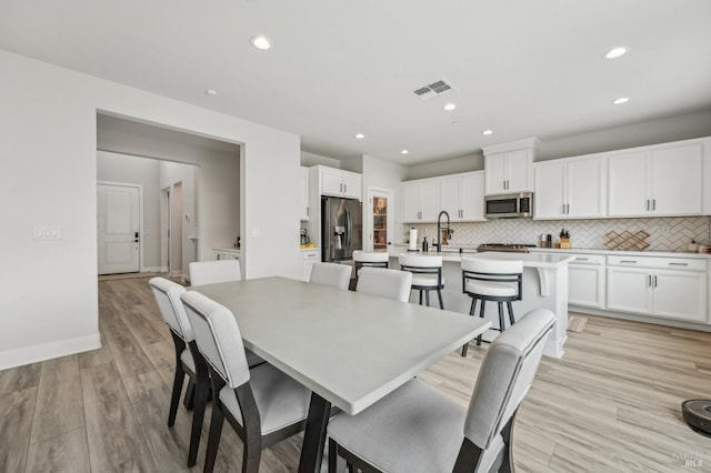 dining room featuring light wood-type flooring, visible vents, baseboards, and recessed lighting