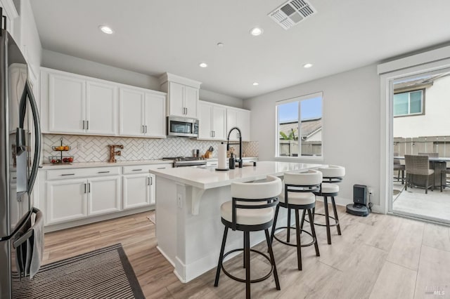 kitchen with white cabinetry, visible vents, stainless steel appliances, and backsplash