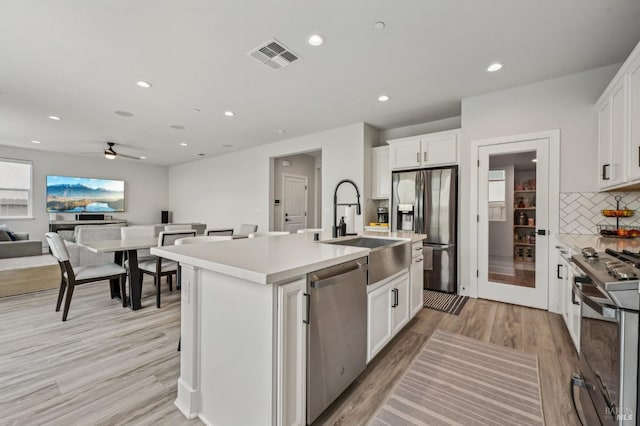 kitchen with light wood-style flooring, a sink, visible vents, white cabinetry, and appliances with stainless steel finishes