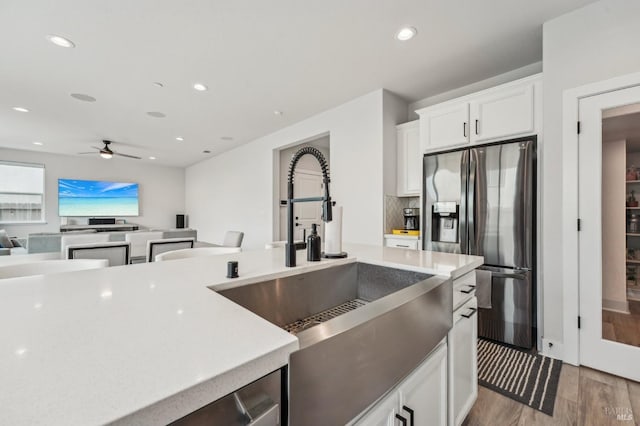 kitchen with recessed lighting, a sink, light wood-type flooring, decorative backsplash, and stainless steel fridge