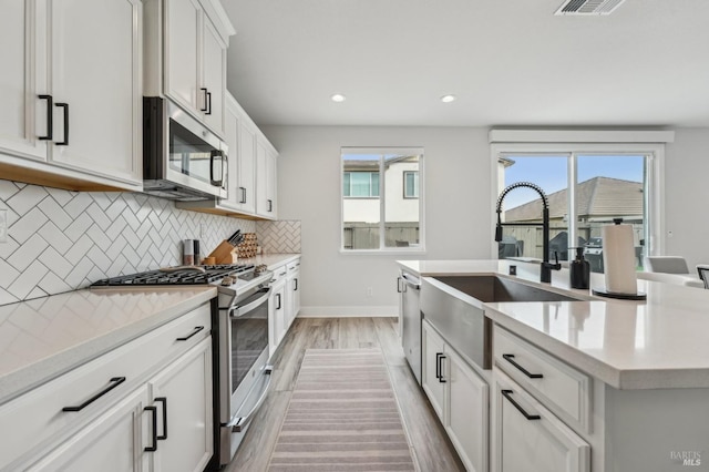 kitchen featuring light countertops, appliances with stainless steel finishes, a sink, and decorative backsplash