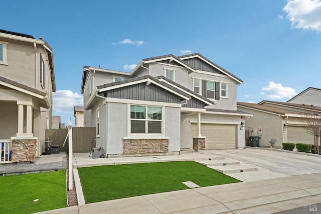 craftsman-style house featuring fence, a garage, stone siding, driveway, and a front lawn