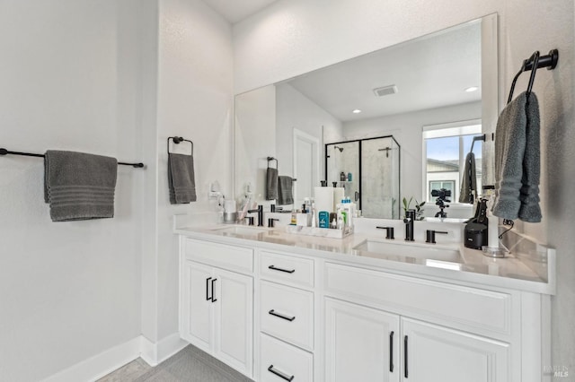 bathroom featuring a sink, a shower stall, baseboards, and double vanity