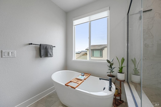 bathroom featuring a freestanding bath, a textured wall, and a marble finish shower