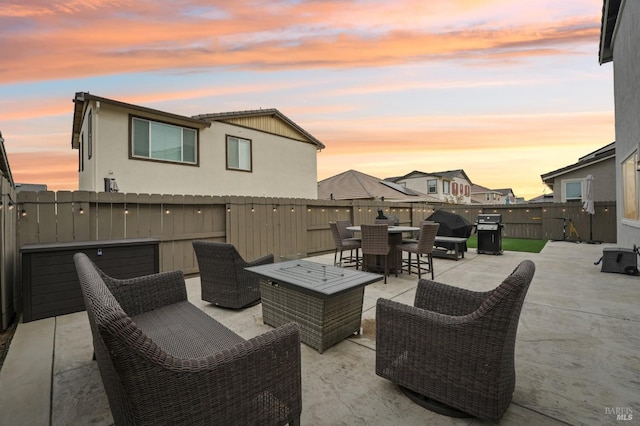 patio terrace at dusk with outdoor dining area, a fenced backyard, a grill, and an outdoor hangout area