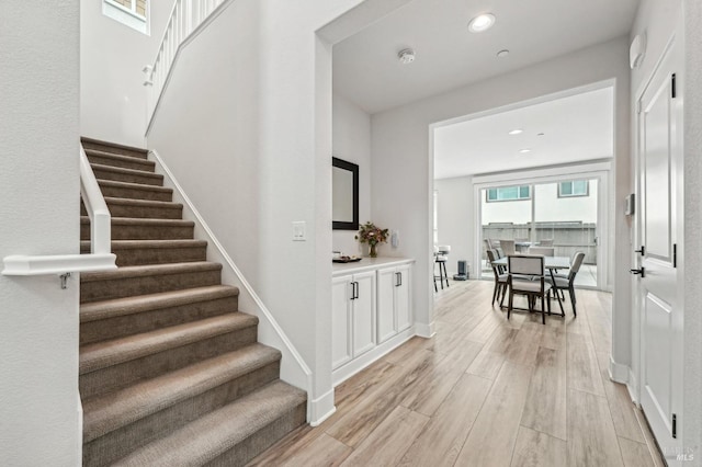 staircase featuring baseboards, wood finished floors, and recessed lighting