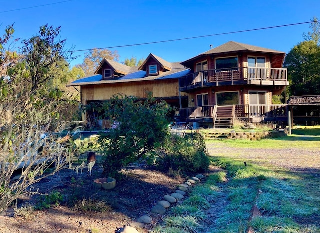 back of property featuring a deck, a lawn, and a balcony