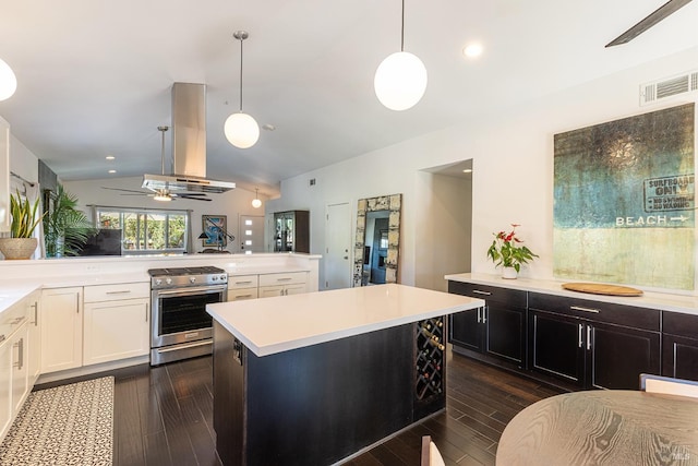 kitchen featuring dark wood finished floors, island exhaust hood, light countertops, gas stove, and vaulted ceiling