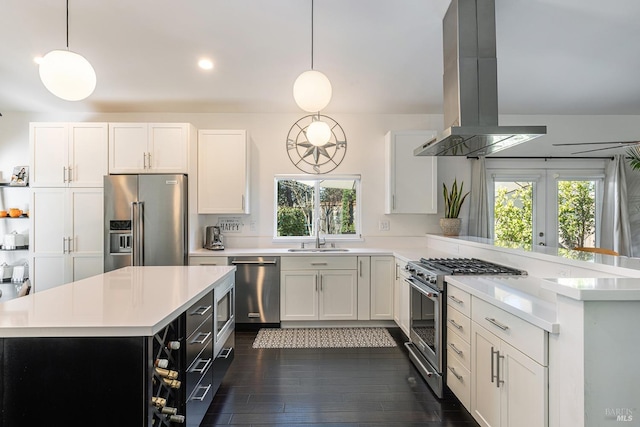 kitchen featuring island exhaust hood, high end appliances, light countertops, a sink, and a peninsula