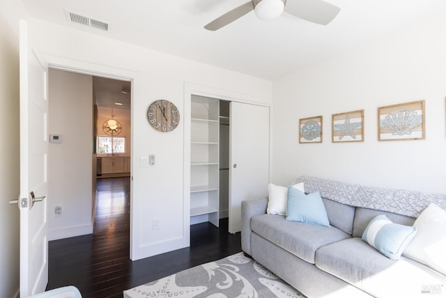 living room featuring baseboards, ceiling fan, visible vents, and dark wood-style flooring