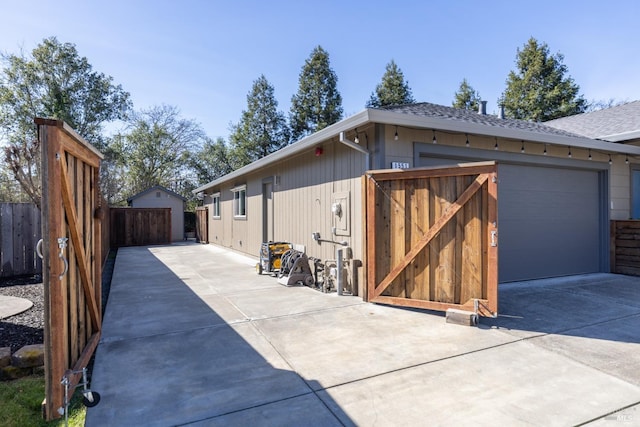 view of home's exterior with a shingled roof, a detached garage, and fence