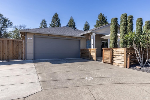 view of front of home featuring a garage, concrete driveway, a shingled roof, and fence