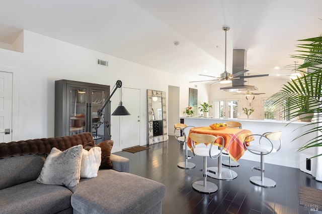 living area featuring lofted ceiling, ceiling fan, visible vents, and wood finished floors