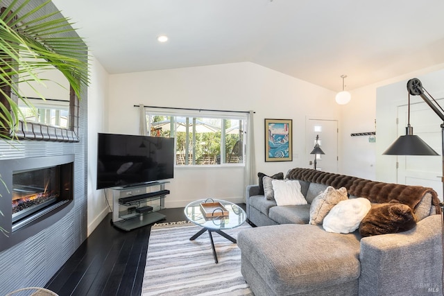 living room featuring lofted ceiling, recessed lighting, wood finished floors, baseboards, and a glass covered fireplace