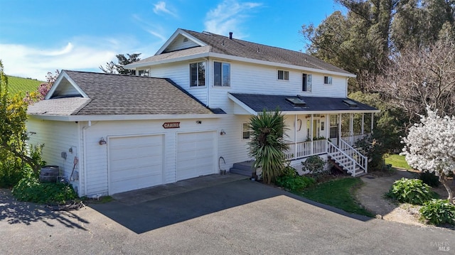 view of front of house featuring an attached garage, covered porch, aphalt driveway, and roof with shingles