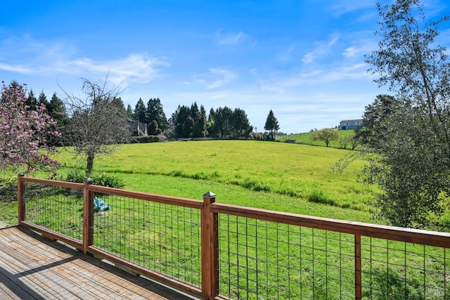 wooden terrace with a yard and a rural view