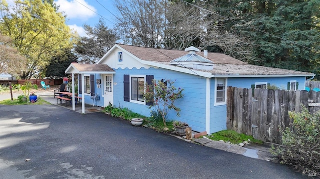 exterior space featuring a shingled roof, fence, and a patio