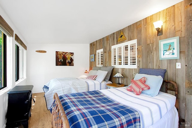 bedroom featuring wood finished floors and wooden walls