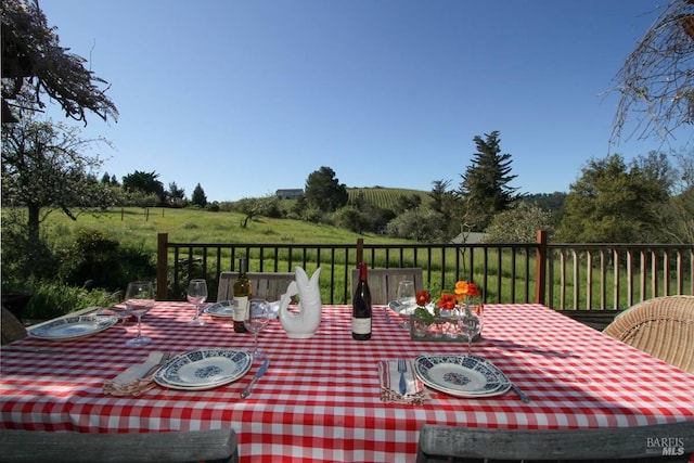 wooden terrace featuring outdoor dining area and a rural view