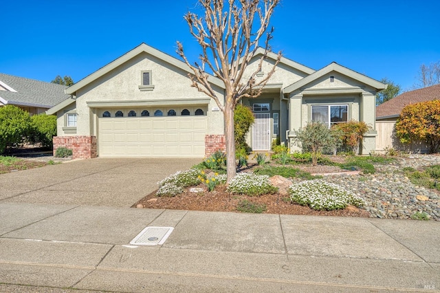 view of front of house featuring concrete driveway, brick siding, an attached garage, and stucco siding