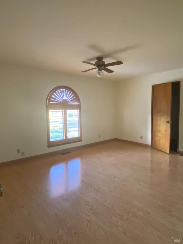 unfurnished room with baseboards, ceiling fan, visible vents, and wood finished floors