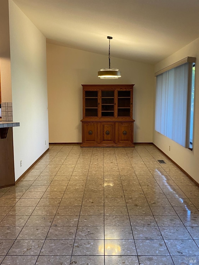 unfurnished living room featuring vaulted ceiling, light tile patterned flooring, and baseboards