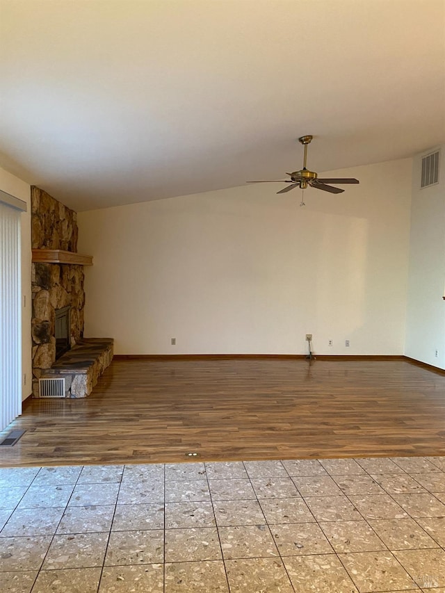 unfurnished living room with ceiling fan, a fireplace, visible vents, and wood finished floors