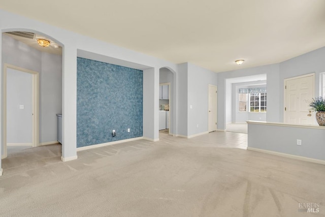 empty room featuring wallpapered walls, baseboards, arched walkways, an accent wall, and carpet floors