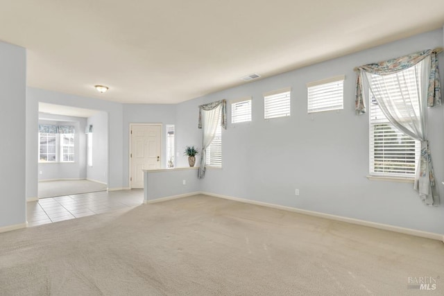 spare room featuring carpet floors, a healthy amount of sunlight, and visible vents