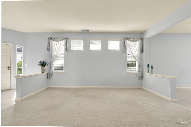 spare room with carpet flooring, visible vents, and baseboards