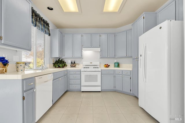 kitchen featuring light countertops, gray cabinetry, light tile patterned flooring, white appliances, and under cabinet range hood