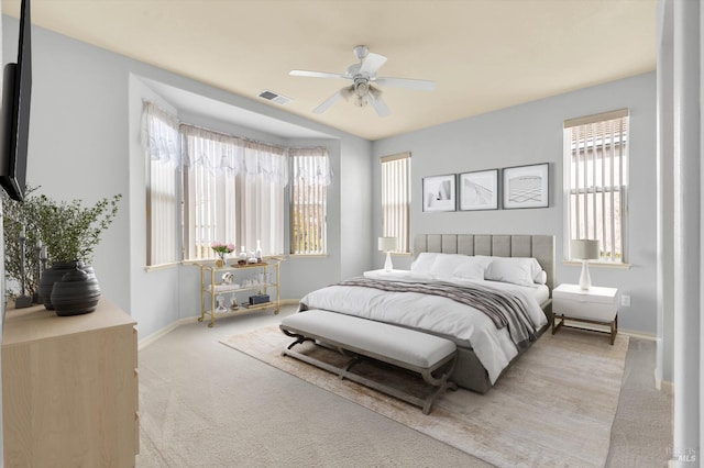 bedroom with baseboards, a ceiling fan, visible vents, and light colored carpet