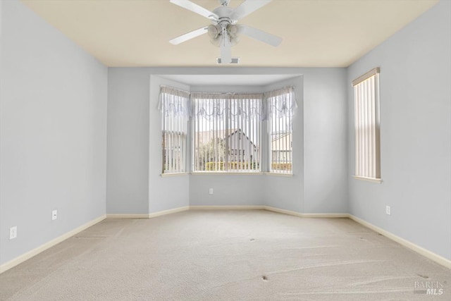 empty room with carpet floors, visible vents, baseboards, and a ceiling fan