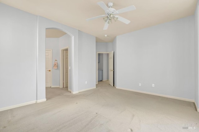 unfurnished bedroom with baseboards, arched walkways, a ceiling fan, and light colored carpet