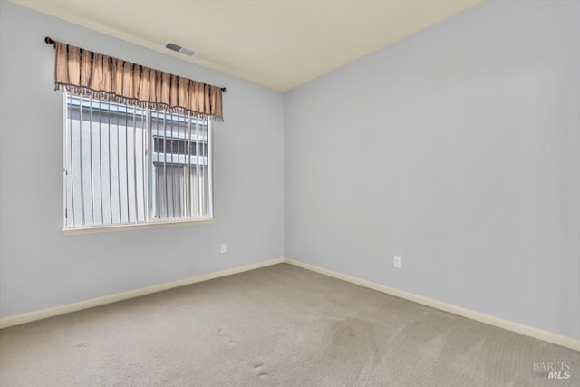 unfurnished room with carpet, visible vents, and baseboards