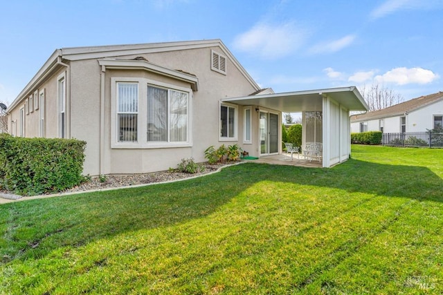 view of front of house featuring a patio area, fence, a front lawn, and stucco siding