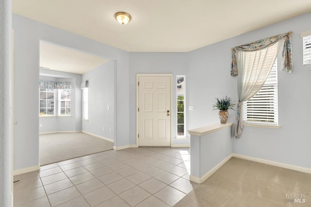 tiled entryway featuring carpet flooring and baseboards