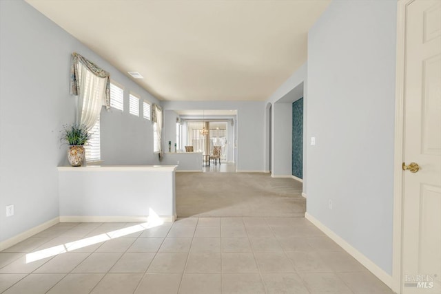 interior space featuring light carpet, visible vents, baseboards, and light tile patterned floors