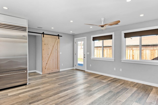 interior space with recessed lighting, a barn door, and wood finished floors