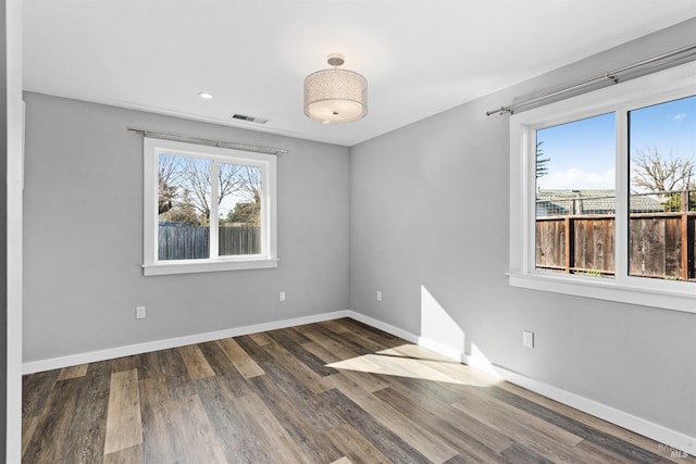 unfurnished room with visible vents, baseboards, and wood finished floors