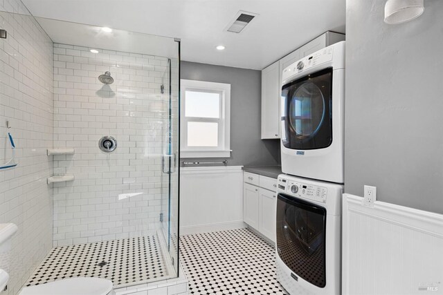 bathroom with stacked washer / dryer, a stall shower, toilet, and visible vents