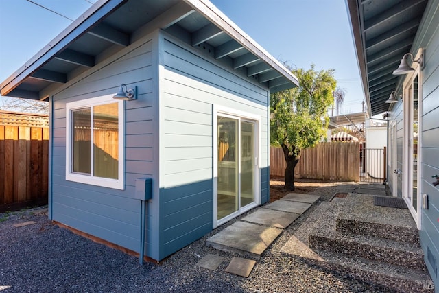 view of side of home with an outdoor structure and fence