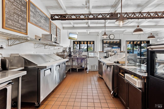 kitchen with light tile patterned floors, dark brown cabinetry, decorative light fixtures, and stainless steel counters