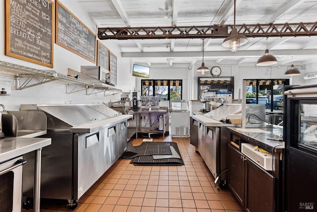 kitchen with light tile patterned flooring, dark brown cabinetry, decorative light fixtures, and stainless steel counters