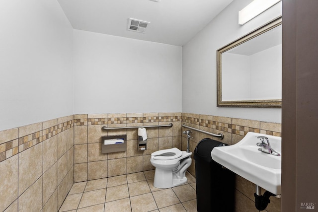 bathroom featuring visible vents, a sink, wainscoting, tile walls, and toilet