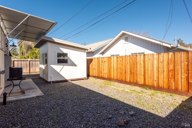 view of yard with an outdoor structure, a fenced backyard, and a patio