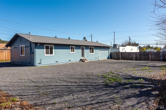 rear view of house featuring fence, driveway, an attached garage, crawl space, and board and batten siding