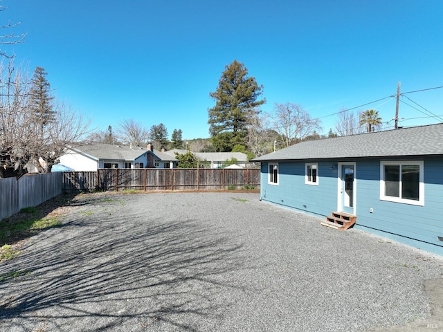 exterior space with a shingled roof, a fenced backyard, and entry steps