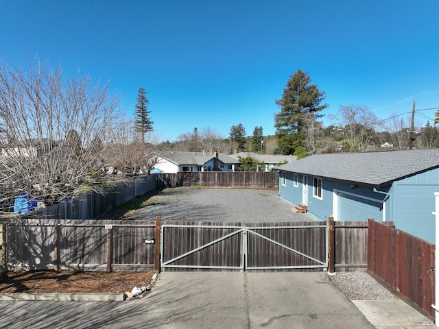 view of yard featuring aphalt driveway, fence, and a gate