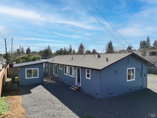 back of house with crawl space, fence, gravel driveway, and entry steps